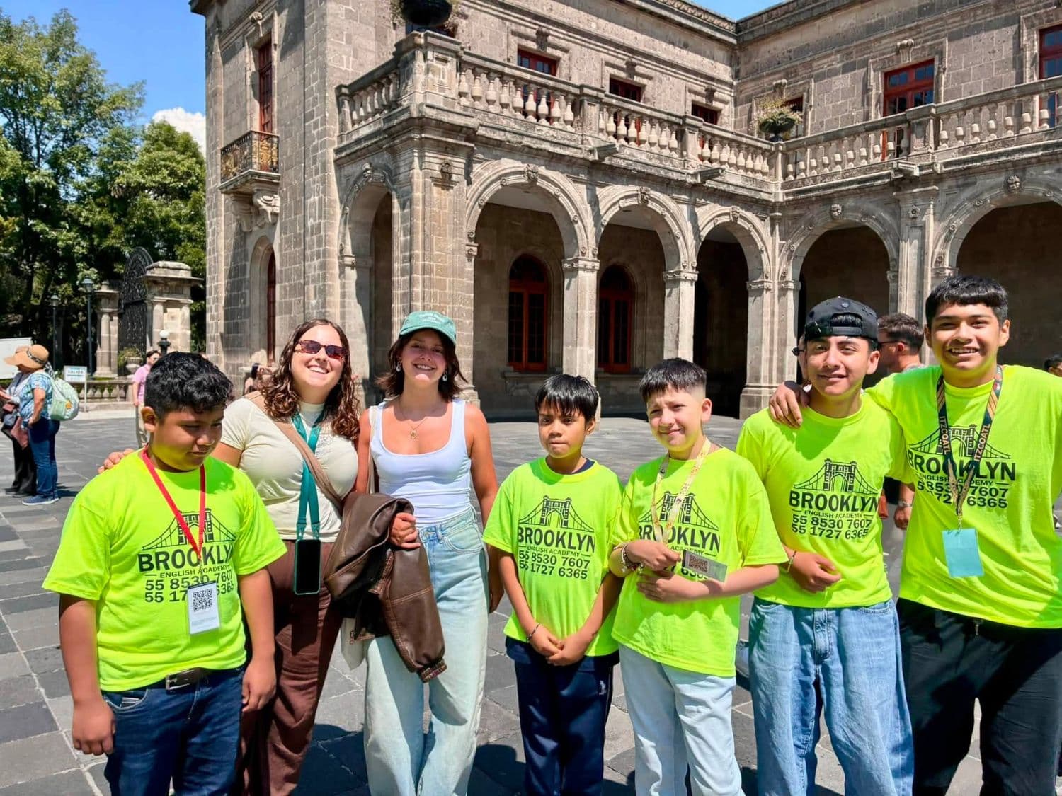 Alumnos de Brooklyn sonriendo junto a dos visitantes extranjeras